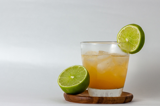 orange drink with ice and lemon on a wooden plate with white background
