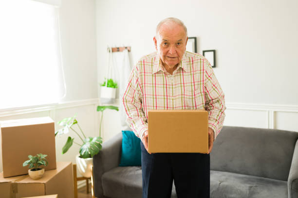 istock Happy old man holding a box while moving into a new apartment or home 1428205130