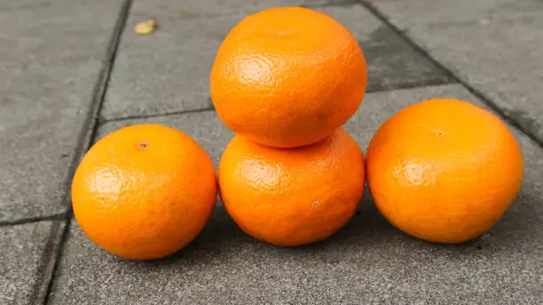 Photo of Four fresh oranges on the stone floor