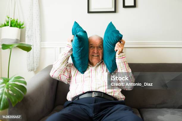 Stressed Old Man Suffering Because Of The Loud Music Of His Neighbors Stock Photo - Download Image Now