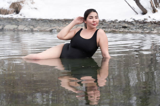 istock Curvy plus size young model in black bathing suit lying in geothermal water in outdoors pool at spa 1428205670