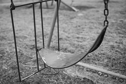 Black and white photography of a swing with the concept of loneliness. Empty park without children.