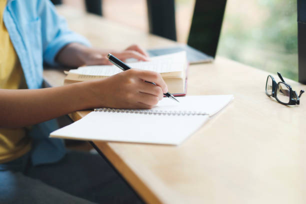 istock Close up of woman studying, reading book, and taking notes. 1428218800
