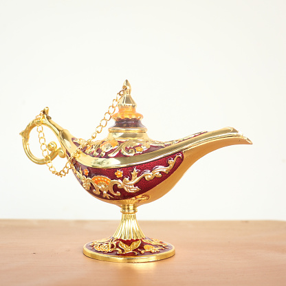 a gold magic lamp said to be holding a genie inside in fantasies isolated in a table in a white background