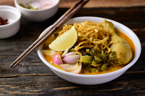 Northern Thai food (Khao Soi), Spicy curry noodles soup with chicken on wooden background, Local Thai food