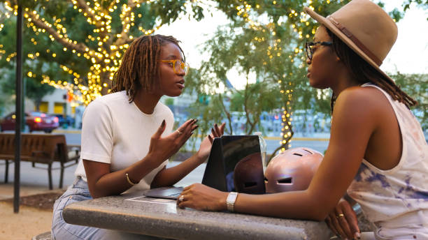 istock Black twin sisters discussing issues while sitting at a public park 1428228154
