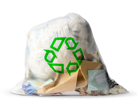 Closed translucent garbage bag with green recycling symbol, isolated on white with clipping path.\nRecycling concepts.