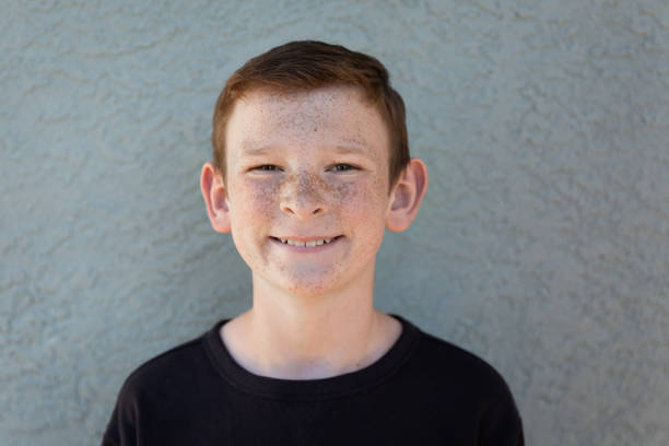 One boy with freckles looking ahead at camera smiling.