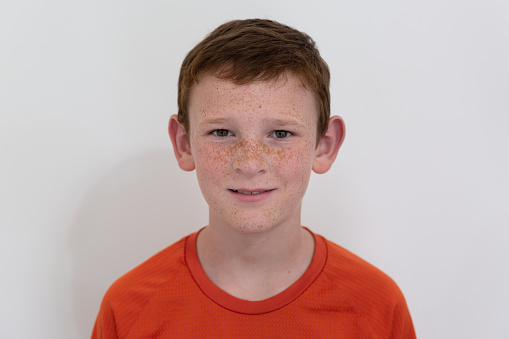 One young boy with red hair and freckles looking at camera and smiling.