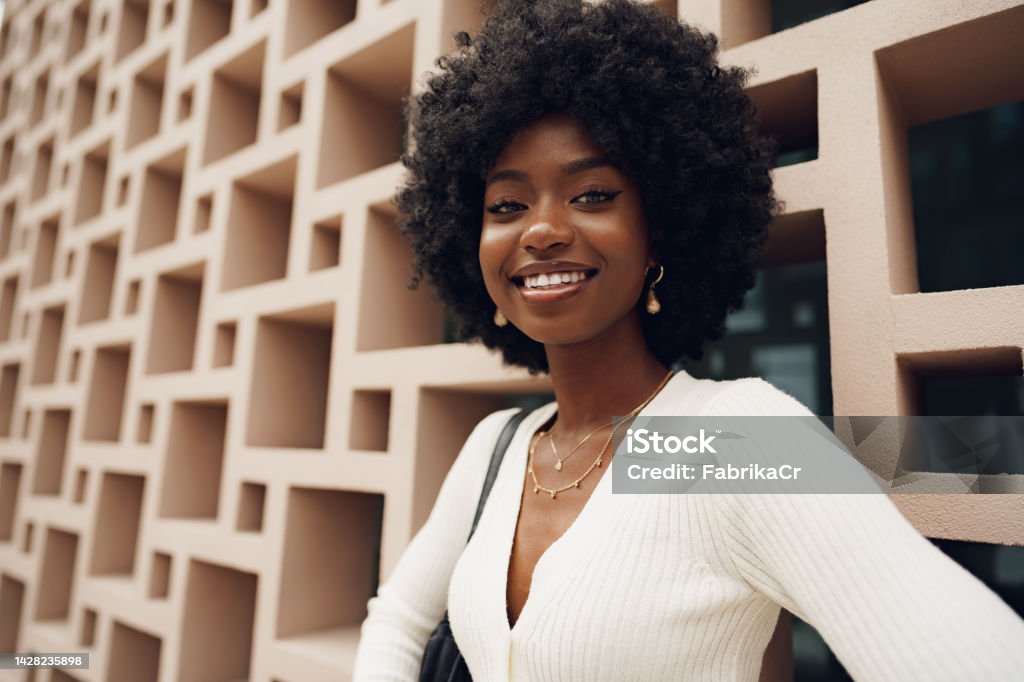 Stylish pretty african woman with Afro hairstyle posing near geometric wall Stylish pretty young african woman with Afro hairstyle posing near geometric wall Women Stock Photo