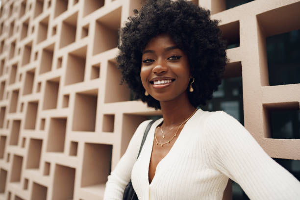 Stylish pretty african woman with Afro hairstyle posing near geometric wall stock photo