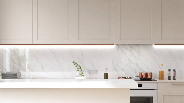istock Modern and luxury beige kitchen island, counter and pantry with white laminated counter top in sunlight from window on white marble wall 1428236680