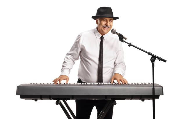 istock Cheerful mature man playing a digital piano and singing on a microphone 1428241073