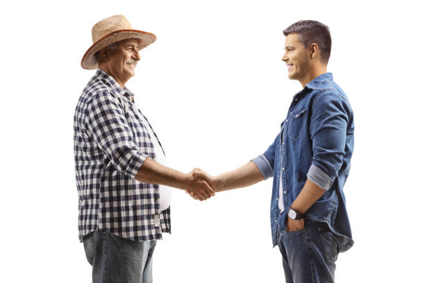 Mature farmer shaking hands with a young casual man stock photo