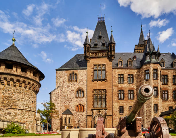 Wernigerode, Germany, September 22, 2022: Wernigerode castle with a medieval cannon and a fountain in the foreground