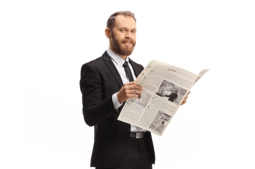 Professional man in a suit standing with a newspaper and smiling at camera isolated on white background