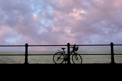 Silhouette of a bicycle on the beach against colorful sunset in the sea,