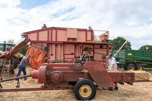 Ilminster.Somerset.United Kingdom.August 21st 2022.Enthusiasts are operating a restored vintage threshing machine at a Yesterdays Farming event