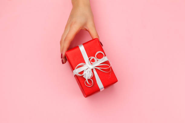 istock Woman holding gift box on color background 1428251535