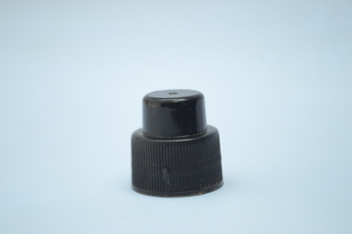 Black small fragrance bottle cap that used to close fragrance and perfume bottle on isolated white background. Portrait taken from flat lay angle.