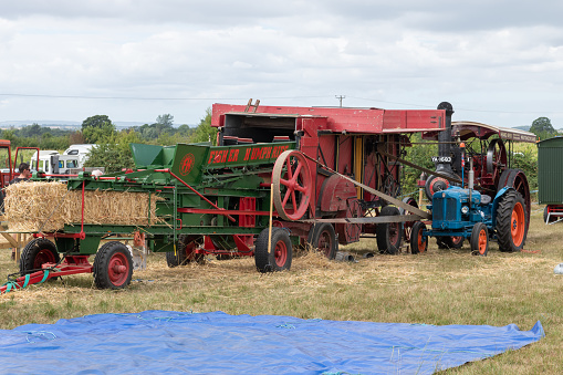 Ilminster.Somerset.United Kingdom.August 21st 2022.A vintage thhreshing machine combined with a Fisher Humphries mark 2 stationary baler are on display at a Yesterdays Farming event