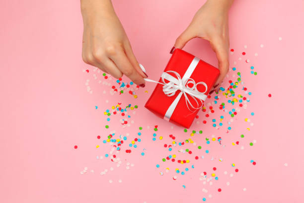 istock Woman holding gift box on color background 1428252631