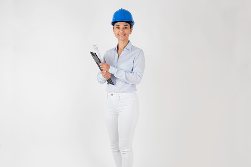 Caucasian female architect wearing blue hard safety helmet in front of white background.