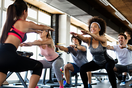 Group of sportive fit people working out in a gym. Multiracial friends exercising together in fitness club.