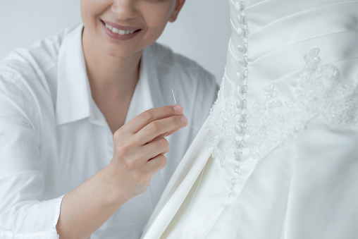 Female trying on wedding dress in a shop with women assistant