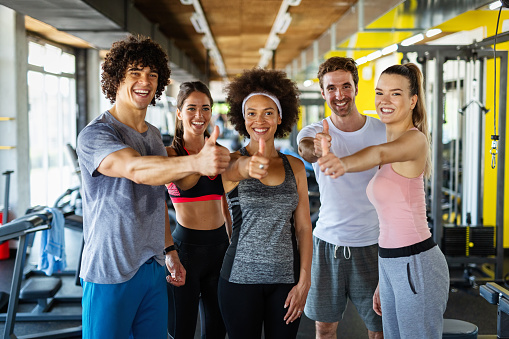 Multiethnic group of people training in a gym. Trainer and sportive fit persons exercising in a fitness class