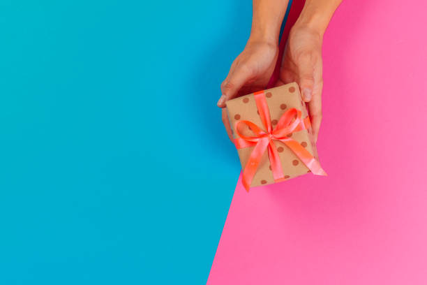 istock Woman holding gift box on color background 1428259153