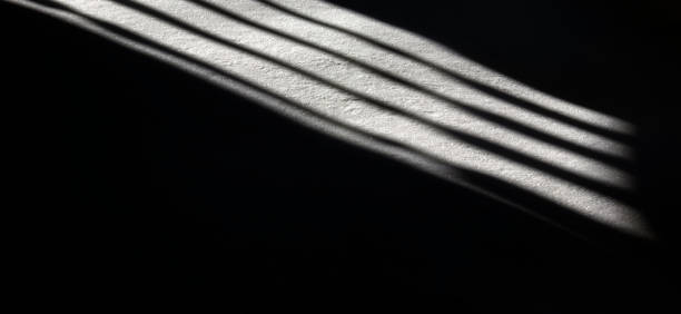 istock Light in the darkness in prison. Abstract reflection of light from a window with bars on the floor 1428260024