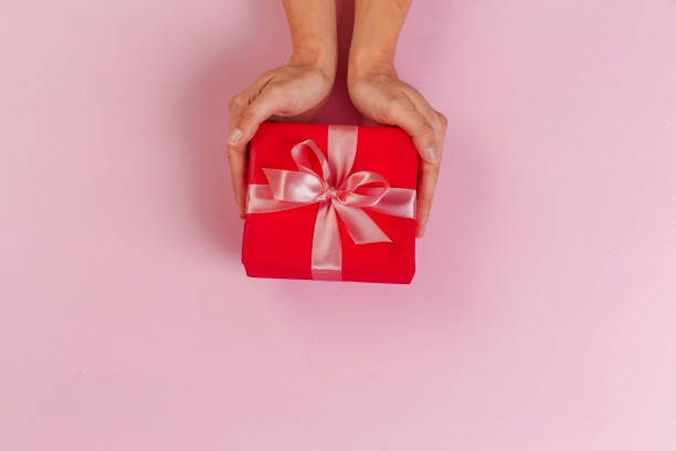 istock Woman holding gift box on color background 1428260495