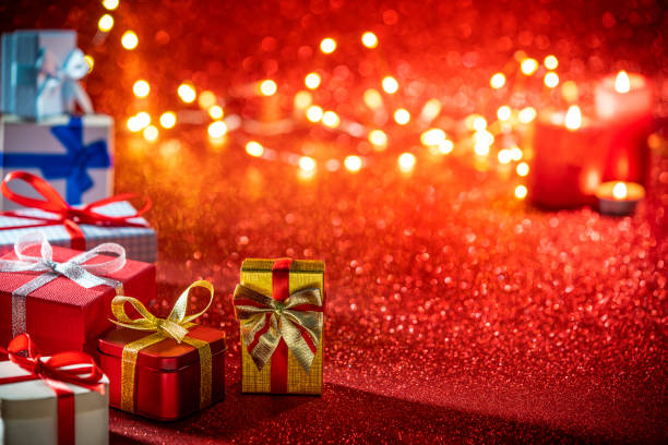 The theme is Valentine's Day. A burning candle and two red candy in the shape of hearts and packed gift are on a white background. Free space for text.