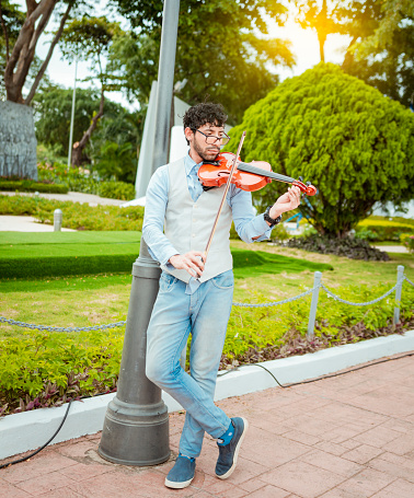 Portrait of man playing violin in the street. Jacket artist playing violin outdoors, Image of a person playing violin outdoors. Man playing violin in the street