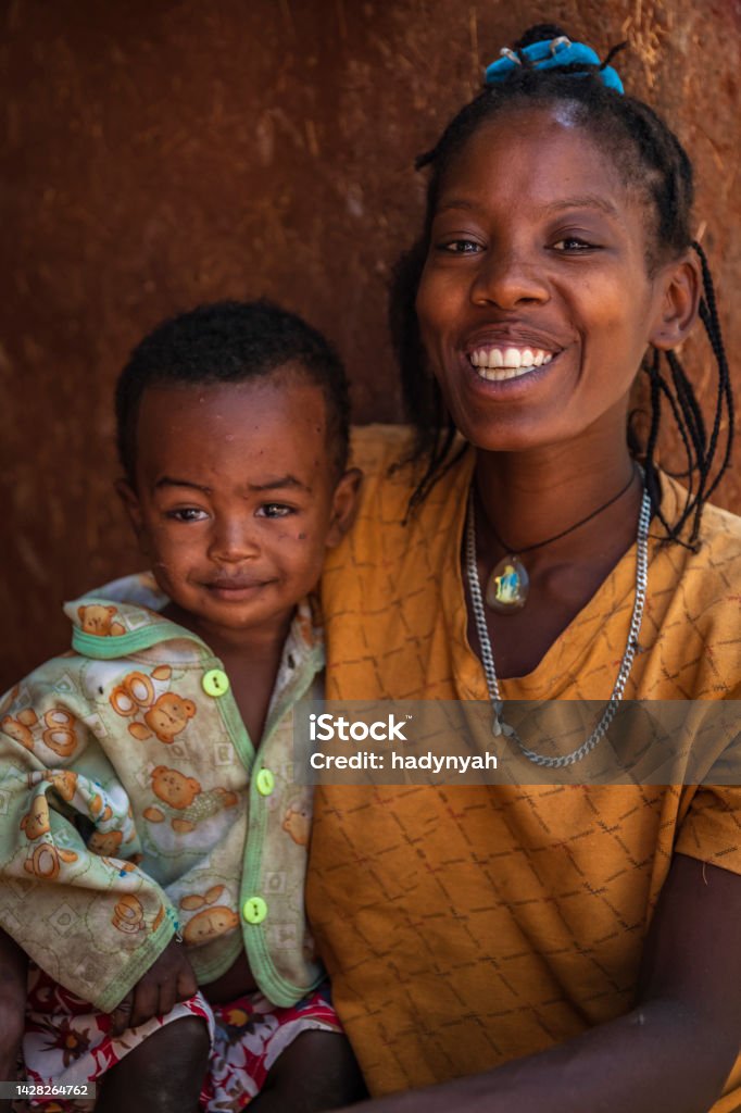 Young African mother with her baby, village near Konso, Ethiopia, Africa Portrait of happy African young woman with her little son. They live in a stone village which is a part of The Konso Cultural Landscape in the Konso highlands of Ethiopia (UNESCO Heritage). Each of these villages has stone walled terraces and fortified houses. Poverty Stock Photo