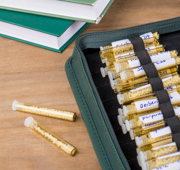 istock Homeopathy globules and vials on a table with books and folder 1428268442