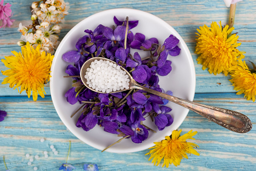 Homeopathy globules and blossoms on a table with spoon and globules