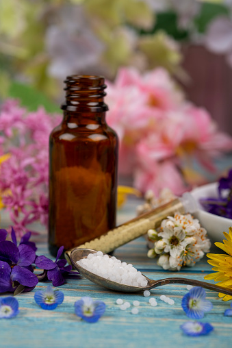 Homeopathy globules and blossoms on a table with spoon and globules