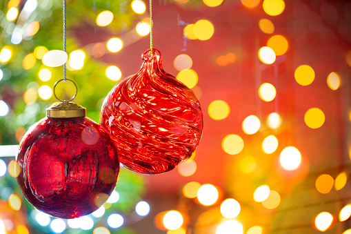 Christmas fir tree background with baubles and glowing Christmas lights bokeh
