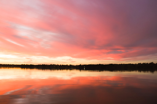 Coral colored surreal cloudscape reflecting on calm tranquil waters.