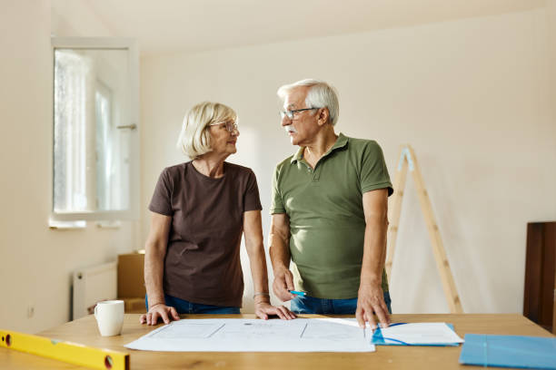 istock Senior couple talking about blueprints during home renovation process. 1428273990