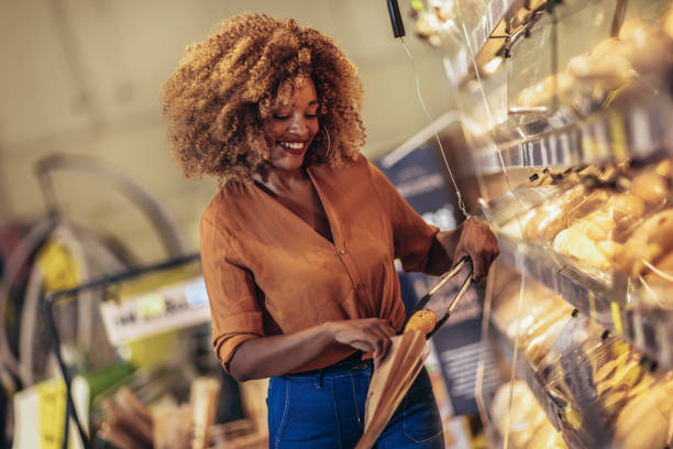 Woman choosing pastries and smiling while doing shopping at the supermarket stock photo