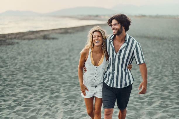 istock Young happy couple taking a summer walk on the beach. 1428275344