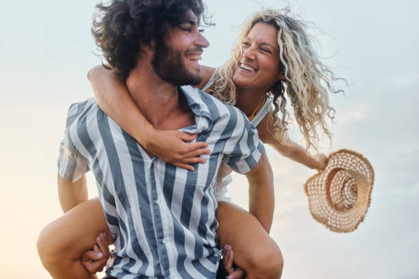 istock Carefree couple talking while piggybacking against the sky. 1428275401