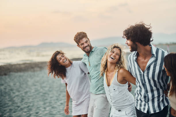 istock Young happy friends talking while walking embraced on the beach. 1428276014