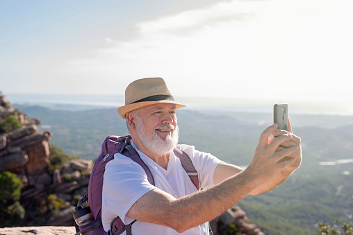 a retired man traveler takes a selfie at the top of the mountain
