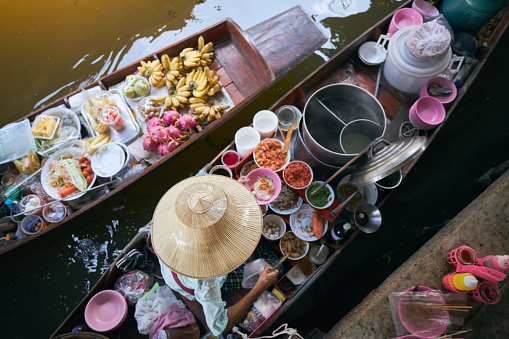 Selective focus on hat of vendor on boat in traditional floating market Damnoen Saduak near Bangkok, Thailand
