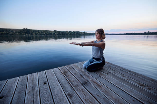 istock Yogi woman meditates and does breathing exercises while sitting on the dock. 1428281013