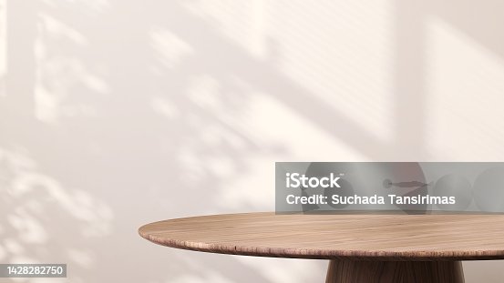 istock Modern round wooden side table with sunlight from window and tropical leaf shadow on white wall background 1428282750